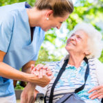 Nurse holding hand of senior woman in pension home