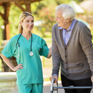home healthcare nurse talks with her senior male patient. The patient is using a walker. They are on the patio at the man's home.