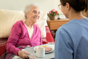 Home caregiver with senior adult woman, serving a meal
