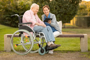 Caregiver and senior man in the park on park bench