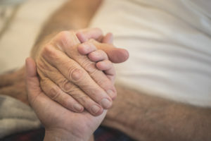 A stock photo of a young woman holding the hands of her Elderly Father who is receiving home hospice care. Photographed using the Canon EOS 1DX Mark II