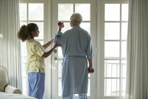 African American nurse helping patient with physical therapy